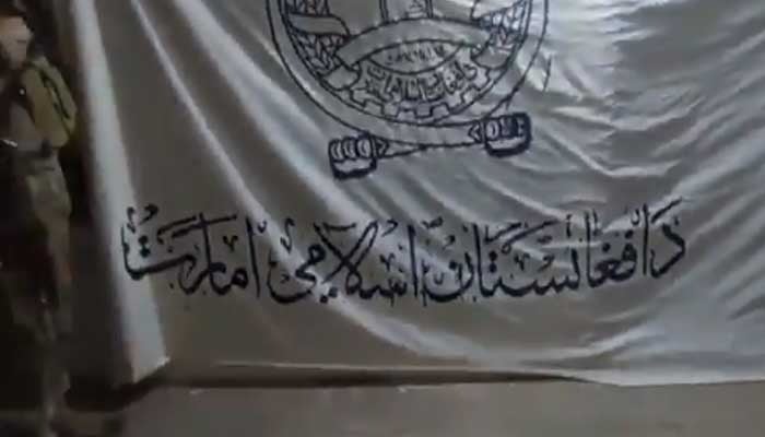 A Pakistan Army soldier stands alongside an Afghan Taliban flag in a captured Afghan post on October 12, 2025. — Screengrab via Geo News