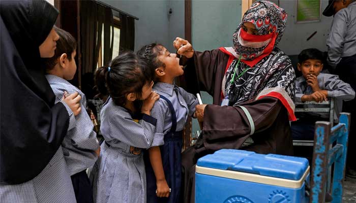 A health worker administers polio drops to school children for vaccination during a door-to-door poliovirus eradication campaign in Lahore on April 21, 2025. — AFP