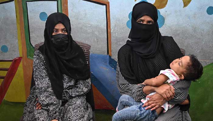 Amina (left), a household helper, sits beside her mother as she speaks during an interview on July 31, 2025 —AFP