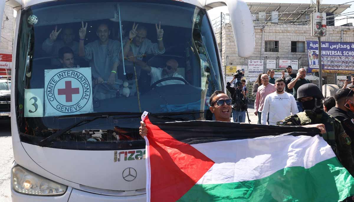 A man holds up a Palestinian national flag in front of a bus carrying former prisoners released by Israeli forces from the Ofer military prison located between Ramallah and Beitunia in the occupied West Bank on October 13, 2025.— AFP