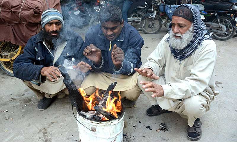 This undated image shows citizens warm their hands around a makeshift fire in Karachi. — APP