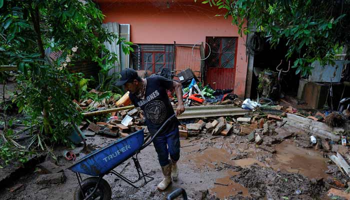 A man uses a wheelbarrow to remove mud and debris from a home as torrential rains from tropical storm Raymond triggered landslides and flooding in Jalcocotan, Nayarit state, Mexico October 12, 2025.— Reuters