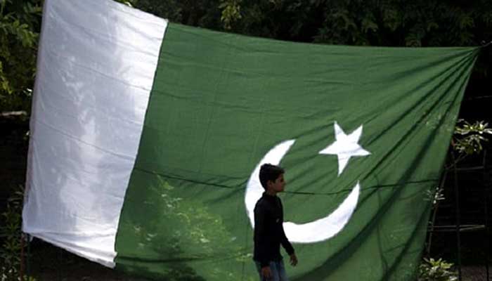 A boy walks past a Pakistani flag in Rawalpindi. — Reuters/File
