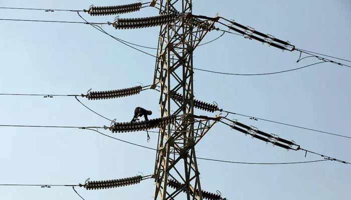 A technician works on porcelain insulators on power transmission tower in Karachi. — Reuters/File