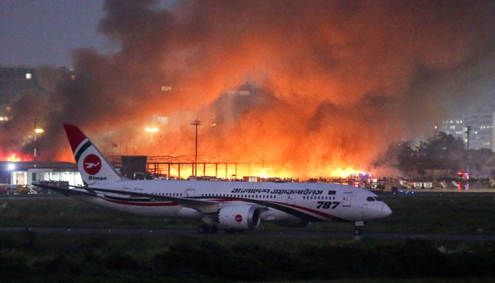 A passenger plane sits on the tarmac, as smoke rises from a fire, which broke out in the cargo bay of the Hazrat Shahjalal International Airport, in Dhaka, Bangladesh, October 18, 2025. — Reuters