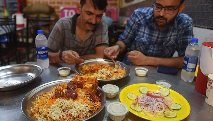 In this photograph taken on September 19, 2023, people eat biryani at a restaurant in Karachi. — AFP/File