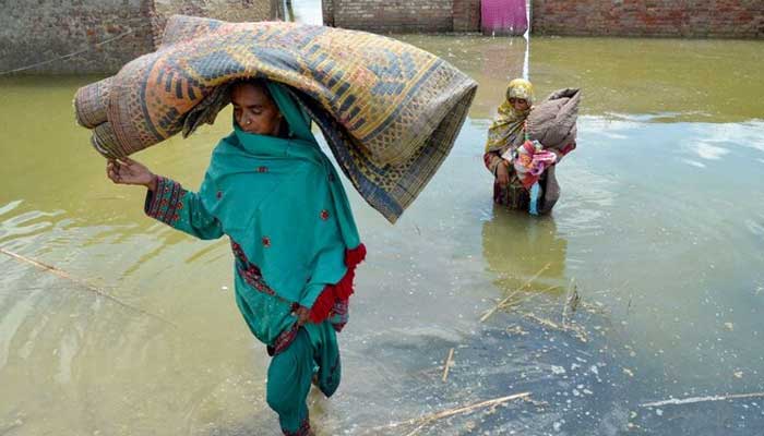Women displaced by flood, carry their belongings as they wade through floodwaters after heavy monsoon rains at Sohbatpur in Jaffarabad district, Balochistan. — AFP/File