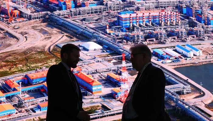 Participants speak in front of an exhibition stand of Russias liquefied natural gas producer Novatek at the Russian Energy Week international forum in Moscow, Russia, October 15, 2025.