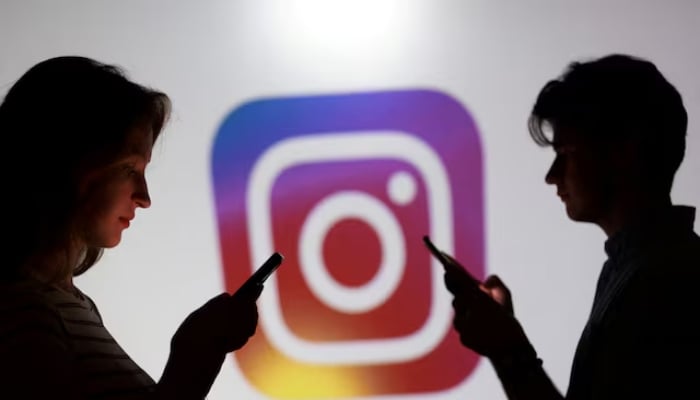 Teenagers pose for a photo while holding smartphones in front of Instagram logo in this illustration taken September 11, 2025. — Reuters