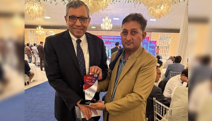 Senior health journalist Waqar Bhatti (right) poses with his National Health Award trophy. — Geo tv
