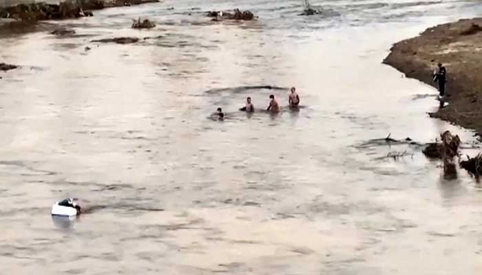 This screengrab from Thai PBS video footage taken in Mae Sot on October 22, 2025 and received by AFPTV on October 23, 2025 shows people crossing a section of the Moei river near KK Park in Myanmar (R) to Thailand. — AFP