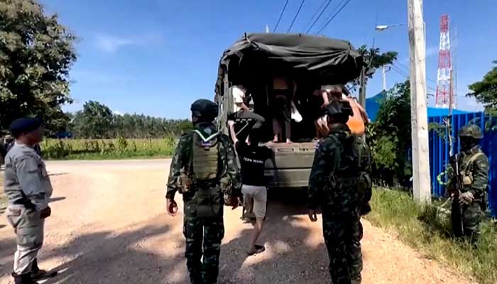 This screengrab from Thai PBS video footage taken on October 22, 2025 and received by AFPTV on October 23, 2025 shows Thai soldiers keeping watch as people, believed to have crossed over to Thailand from Myanmar after escaping from scam centres, board a vehicle in Mae Sot. — AFP