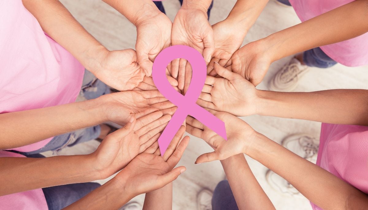 A representational image of women holding a pink ribbon to symbolising breast cancer awareness. — Canva