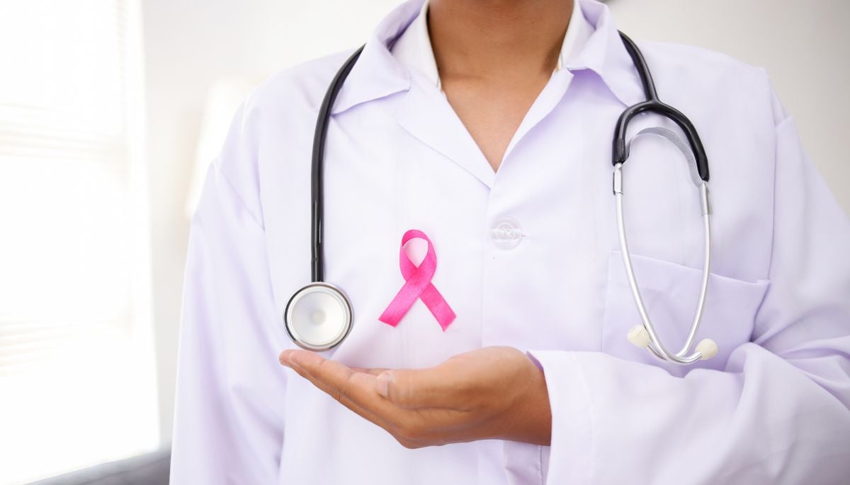 A representational image of a doctor wearing a pink ribbon symbolising breast cancer awareness. — Canva