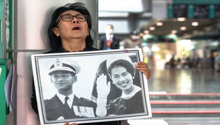 Thai mourner Kanjana Malaithong holds portraits of Thailand´s former queen Sirikit as she walks at Chulalongkorn Hospital in Bangkok on October 25, 2025. — AFP