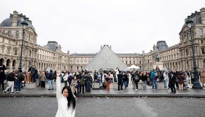 People stand near the glass Pyramid of the Louvre Museum as the museum remains closed the day after a spectacular jewel heist in Paris, France, October 20, 2025.— Reuters