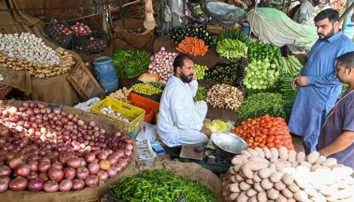 People buy vegetables at a local market in Lahore. — AFP/File