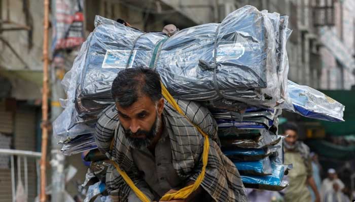 A labourer delivers packs of fabrics to a market in Karachi. — Reuters