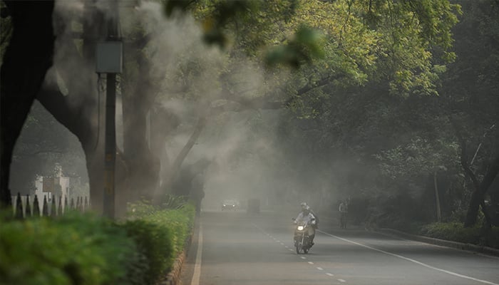 Men ride a bike as they pass an anti-smog misting system installed on a road on a smoggy morning after air quality dips, partly due to the use of firecrackers during the Diwali festival in New Delhi, India, October 22, 2025. — Reuters