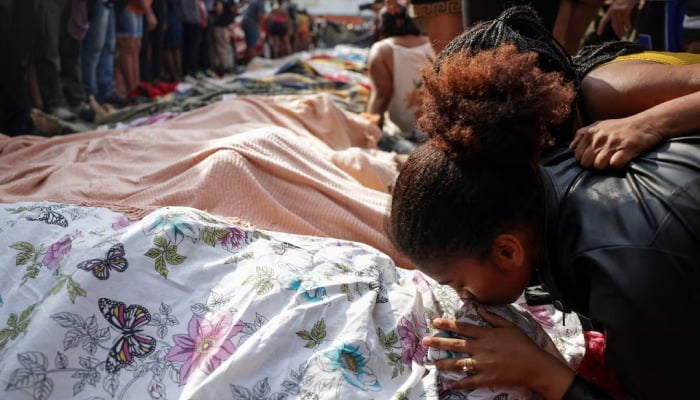 A mourner kisses a covered body, the day after a deadly police operation in Rio de Janeiro, on October 29, 2025. — Reuters