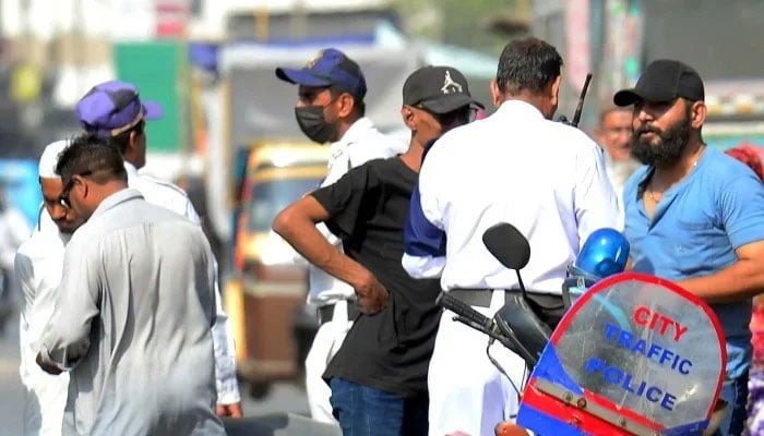 Traffic police officials charge a challan for violating the traffic rules, at Saddar area in Karachi on Tuesday, April 15, 2025. — PPI