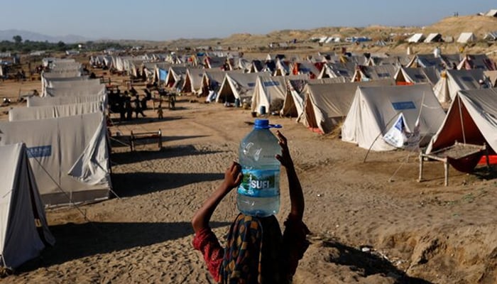 A displaced girl carries a bottle of water she filled from nearby stranded flood-waters, as her family takes refuge in a camp, in Sehwan, Pakistan, September 30, 2022. — Reuters