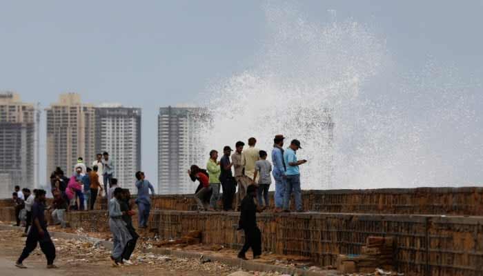People gather near the rising waves at Clifton Beach, in Karachi, on June 13, 2023. — Reuters