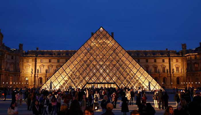 People walk near the glass Pyramid of the Louvre museum  as French police have arrested more suspects linked to the theft of treasures from the Louvre museums Galerie dApollon, in Paris, France, October 30, 2025. — Reuters