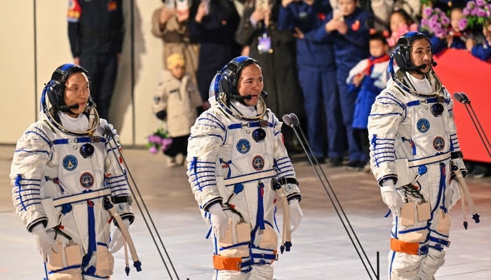 Astronauts for Chinas Shenzhou-21 space mission, Zhang Hongzhang (L), Commander Zhang Lu (C) and Wu Fei (R), wave during a departure ceremony before boarding a bus to take them to the Shenzhou-21 spaceship at the Jiuquan Satellite Launch Centre in the Gobi Desert in northwest China on October 31, 2025. — AFP