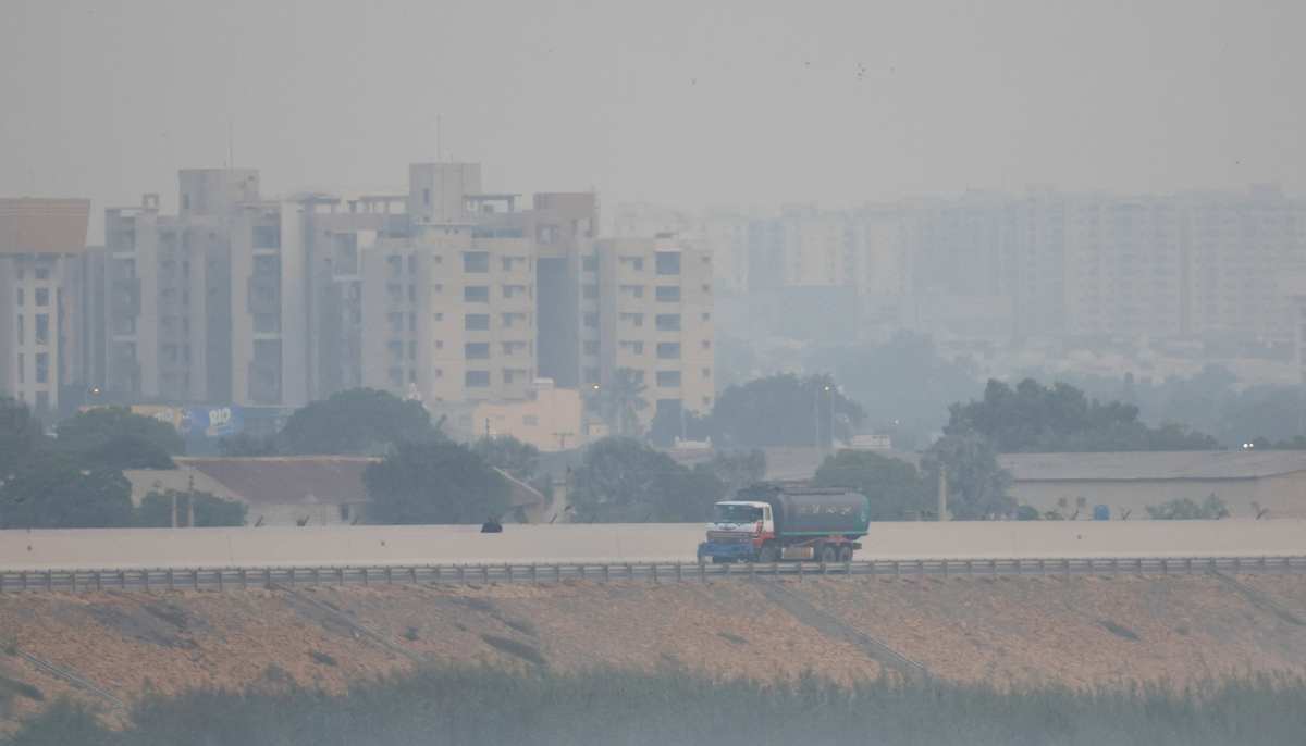 A vehicle drives past buildings in the background amid smog and air pollution in the morning, in Karachi on October 31, 2025. — Reuters