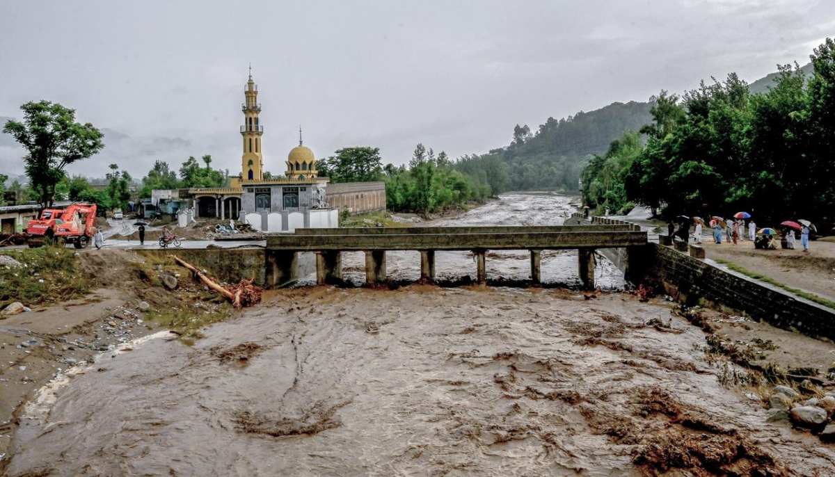 Villagers stand near a bridge as floodwater levels rise in the Buner district of Khyber Pakhtunkhwa on August 18, 2025. — AFP