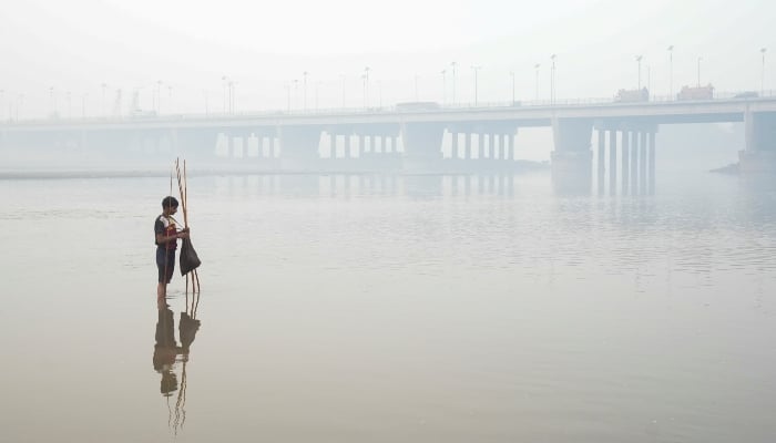 5 نومبر ، 2024 کو لاہور ، پاکستان میں اسموگ کے درمیان ، پس منظر میں دریائے روی کے پل کے ساتھ ، فہیم نے ماہی گیری کا جال بچھایا۔