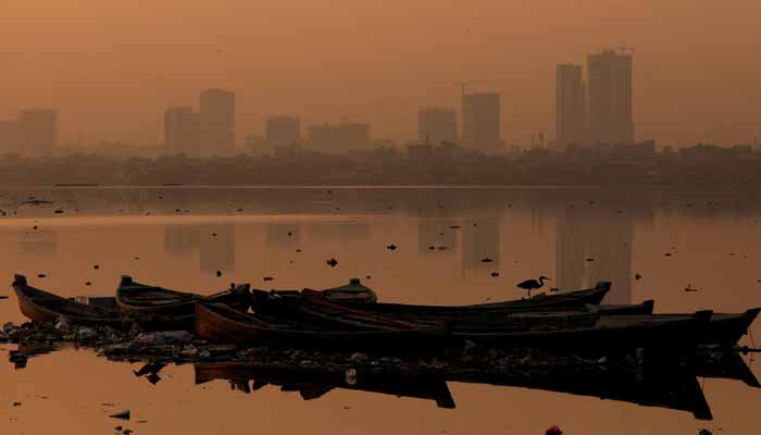 A bird sits on an anchored fishing boat, with buildings in the background amid smog and air pollution, in the morning, in Karachi, Pakistan, October 23, 2025. — Reuters
