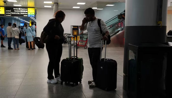 Travelers use a mobile phone at Terminal 8 at John F. Kennedy International Airport in New York, US, June 8, 2025. — Reuters