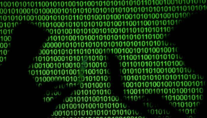 Silhouettes of laptop users are seen next to a screen projection of binary code in this picture illustration. — Reuters