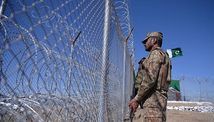 A soldier stands next to a border fence along Afghanistans Paktika province in Angoor Adda, Pakistan. — AFP/File