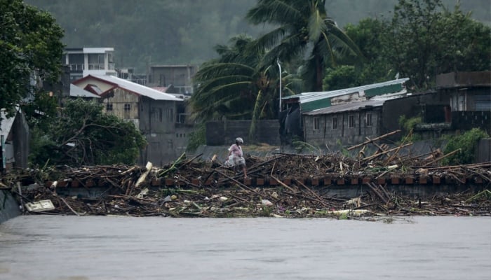 A man walks past debris along the shores of a river at Polangui in Albay province, south of Manila on November 9, 2025, after Super Typhoon Fung-wong made landfall. — AFP