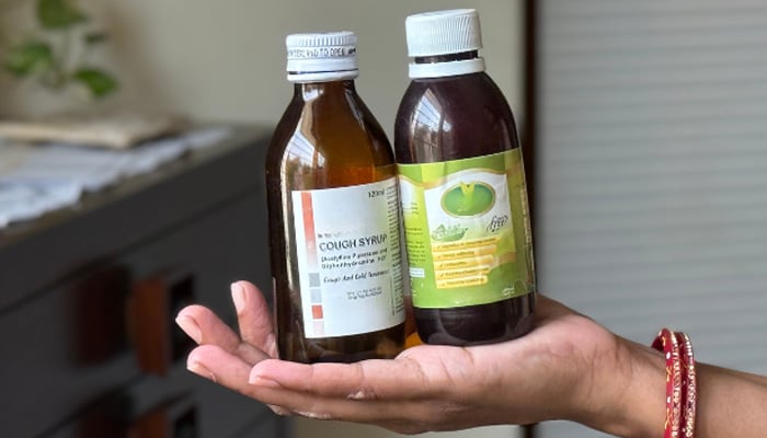 Rakhi Matan holds bottles of cough syrup in her palm. This is what she gave to her kids two weeks back when they were feeling ill. — IPS
