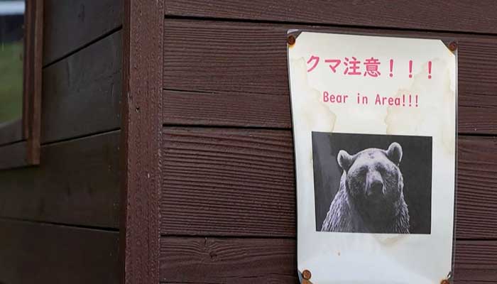 This screen grab taken from AFPTV video footage filmed on October 25, 2025 shows a Bear in Area warning sign displayed near a forest in Akita Prefecture. — AFP