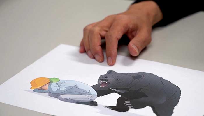 This screen grab from AFPTV video footage taken on October 26, 2025 shows Akita University Hospital´s Professor of Emergency and Critical Medicine Hajime Nakae showing a bear attack safety illustration in Akita. — AFP