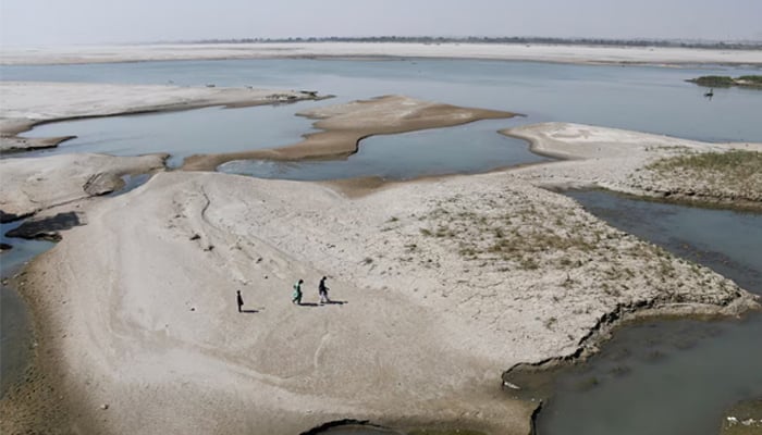 People walk on the dry patch of the Indus River, in Jamshoro March 15, 2025. — Reuters
