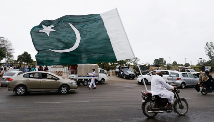 A man with a national flag on his bike rides during the celebrations of Independence Day in Karachi on August 14. — Reuters