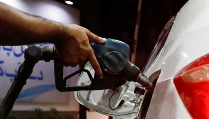 A worker holds a fuel nozzle to fills fuel in a car at a petrol station in Karachi. — Reuters/File