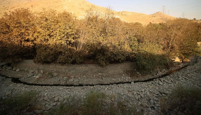 A trickle of water flows in the mainly dried-up Kan River, west of Tehran, on November 9, 2025, as Iran faces severe water shortages. — AFP