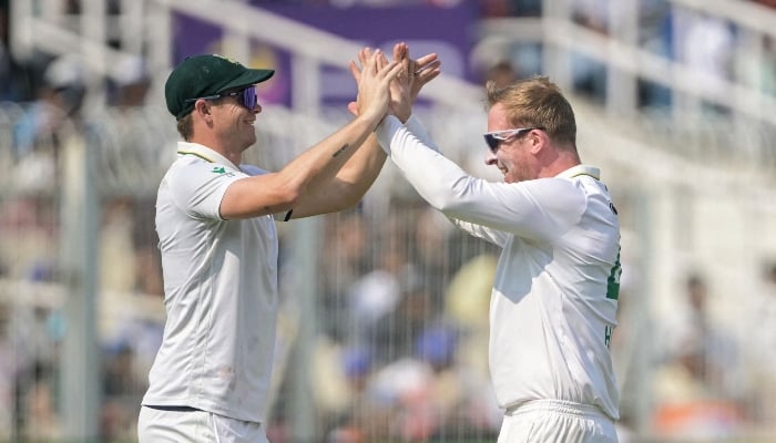 South Africa´s Simon Harmer (R) celebrates with teammate after taking the wicket of Indias Dhruv Jurel during the third day of the first Test cricket match between India and South Africa at the Eden Gardens in Kolkata on November 16, 2025. — AFP