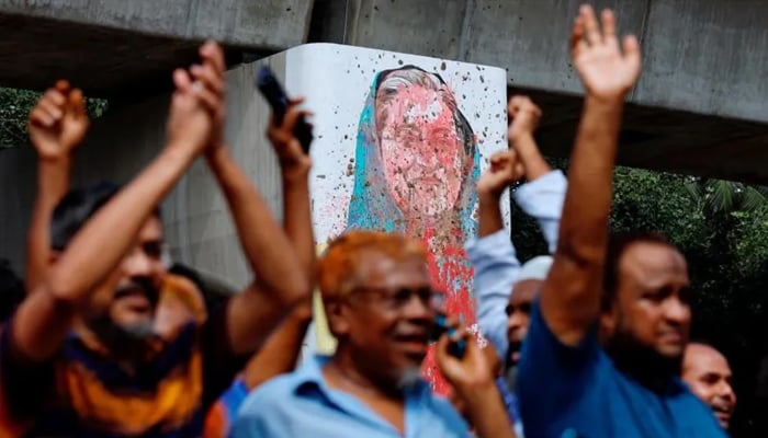Protestors chant slogans with ex-PM Hasinas disfigured portrait in the background amid deadly 2024 protests that led to autocratic rulers exit from government. — Reuters