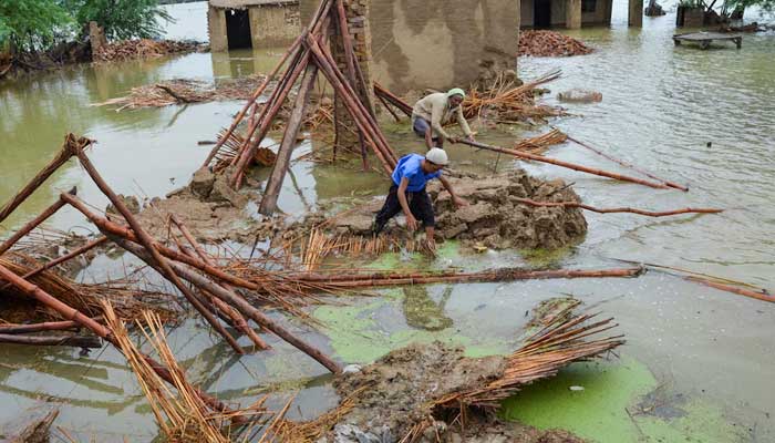 People retrieve bamboos from a damaged house following rains and floods during the monsoon season in Dera Allah Yar, district Jafferabad, Balochistan. — Reuters/File