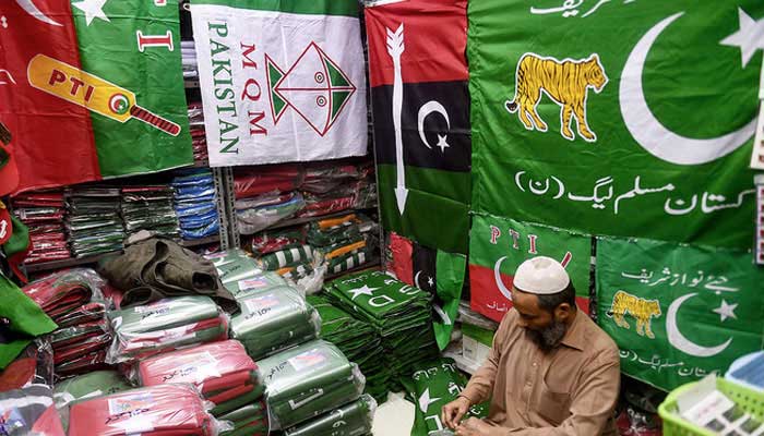 A shopkeeper arranges flags of political parties at his shop before the February 8 general elections in Karachi on January 3, 2024. — APF