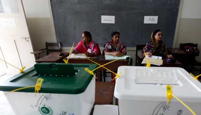 Polling staff pictured alongside ballot boxes at a polling station. — Reuters/File