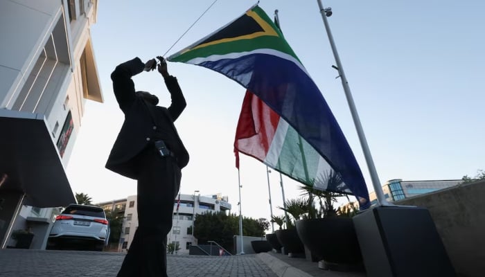 A worker raises the South African flag in Sandton on the morning of the first day of the G20 Summit, in Johannesburg, South Africa, November 22, 2025. — Reuters